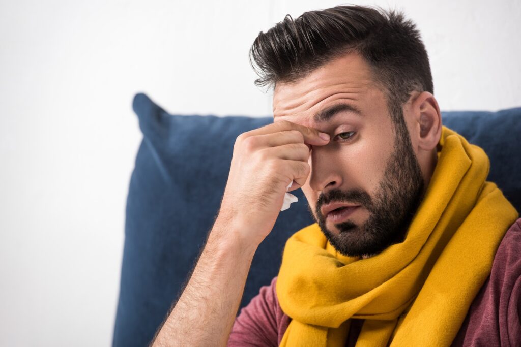 close-up portrait of sick young man with sinus infection touching his nose