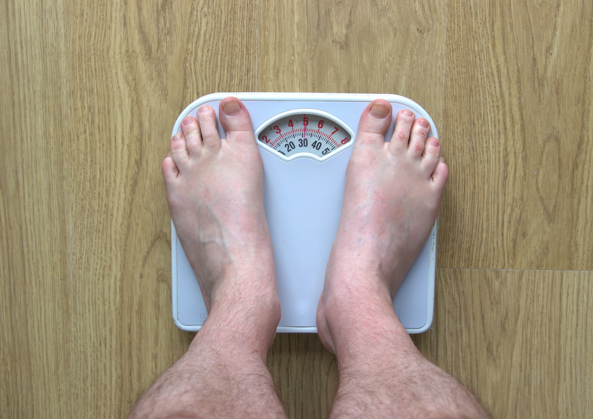 Man's feet standing on bathroom scales
